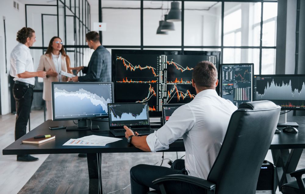 Man trading shares on multiple computer screens